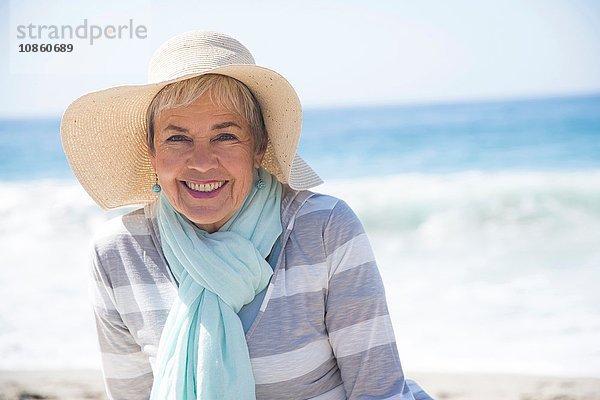 Porträt einer älteren Frau  die sich am Strand entspannt und lächelt
