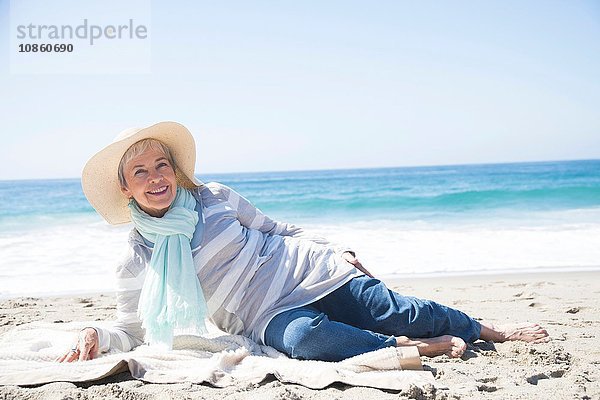 Porträt einer älteren Frau  die sich am Strand entspannt und lächelt