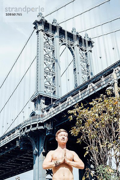 Mann meditiert mit den Händen zusammen vor der Manhattan Bridge  New York  USA