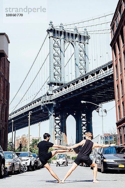 Zwei seitwärts geneigte Männer in Yogaposition vor der Manhattan Bridge  New York  USA