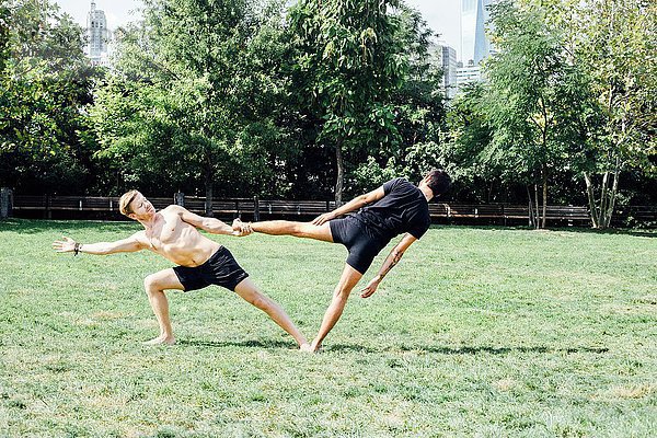 Zwei Männer  die sich im Yoga-Fuß seitwärts lehnen  halten Position im Park