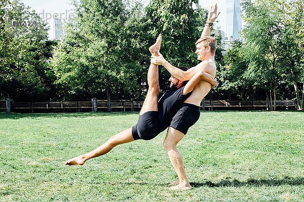 Zwei Männer üben Yoga-Lift-Position im Park