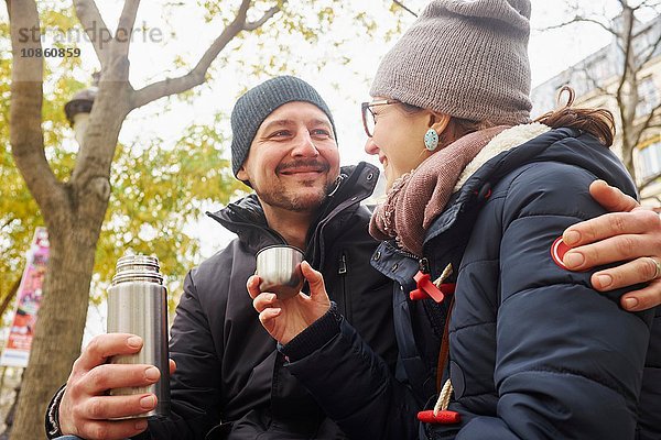 Paar mit Strickmützen mit Getränkeflasche im Park