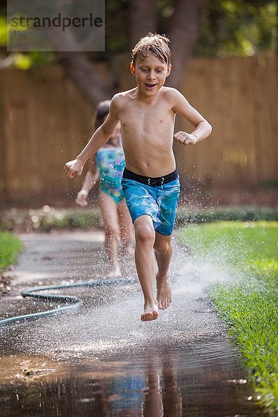 Kinder laufen im Wasser auf dem Bürgersteig