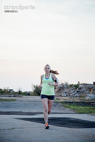 Vorderansicht einer Frau in voller Länge  die einen Aktivitäts-Tracker beim Joggen trägt