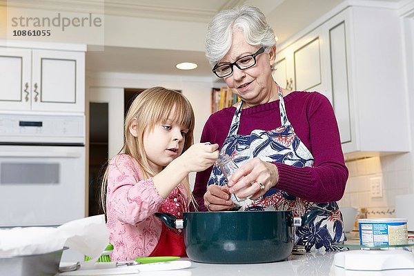 Mädchen und Großmutter messen Salz zum Kochen