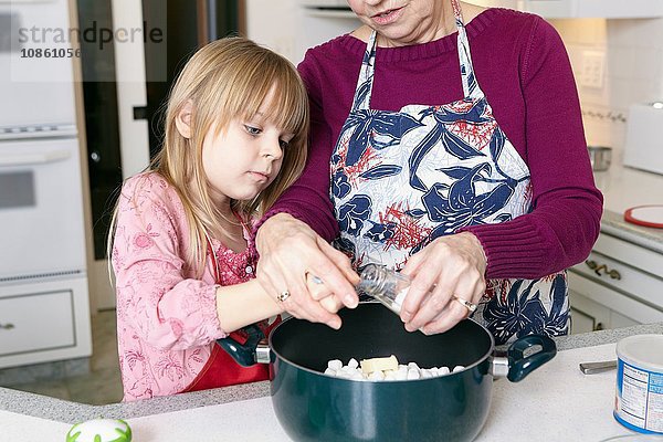 Mädchen und Großmutter messen Salz für Kasserolle