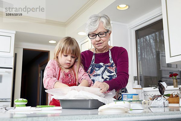Mädchen und Großmutter bereiten an der Küchentheke fettdichtes Papier vor
