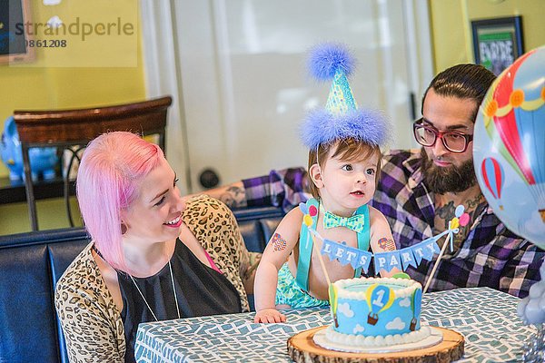 Junge erwachsene Eltern mit kleinem Sohn bei der ersten Geburtstagsfeier
