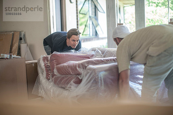 Umzug: zwei Männer heben blasenverpacktes Sofa