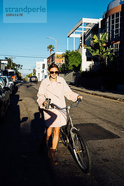 Junge stilvolle Frau schiebt Fahrrad die Straße entlang   Venice Beach  Kalifornien  USA