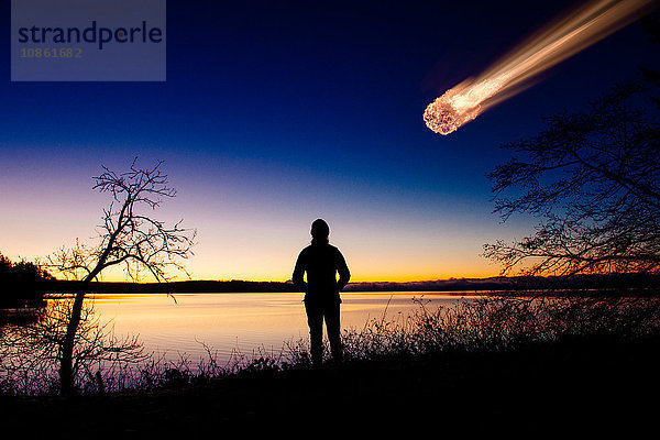 Silhouette eines Erwachsenen  der einen Meteor beobachtet  der in den Nachthimmel fällt