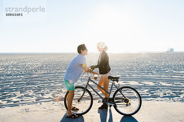 Junges Paar mit Fahrrad beim Plaudern am sonnigen Strand  Venice Beach  Kalifornien  USA
