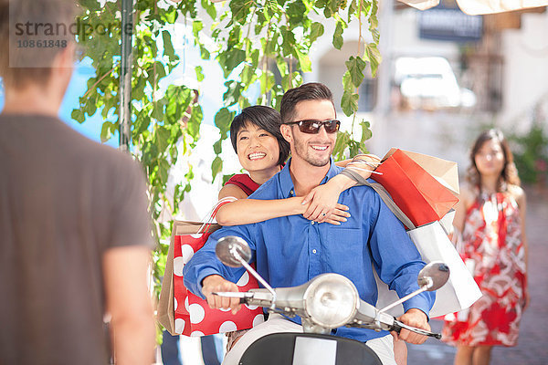 Romantisches junges Paar mit Einkaufstaschen auf dem Moped in der Stadt