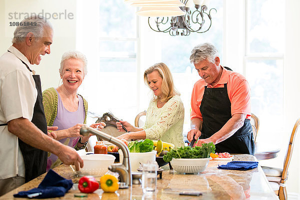 Gruppe von Senioren  die in der Küche eine Mahlzeit zubereiten
