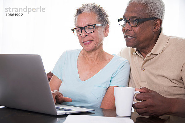Älteres Ehepaar am Tisch sitzend  mit Laptop