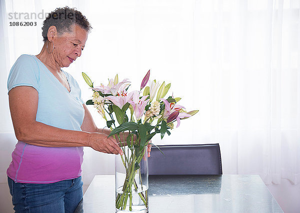 Ältere Frau arrangiert Blumenvase