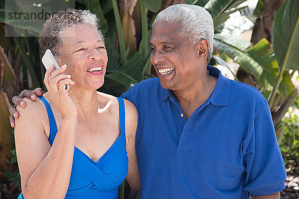 Älteres Paar sitzt im Freien  benutzt Smartphone  lächelt