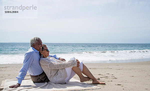 Älteres Ehepaar entspannt sich gemeinsam am Strand und schaut sich die Aussicht an
