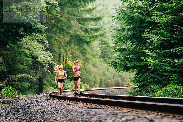 Junge Frau und jugendliches Mädchen rennen entlang ländlicher Zuggleise