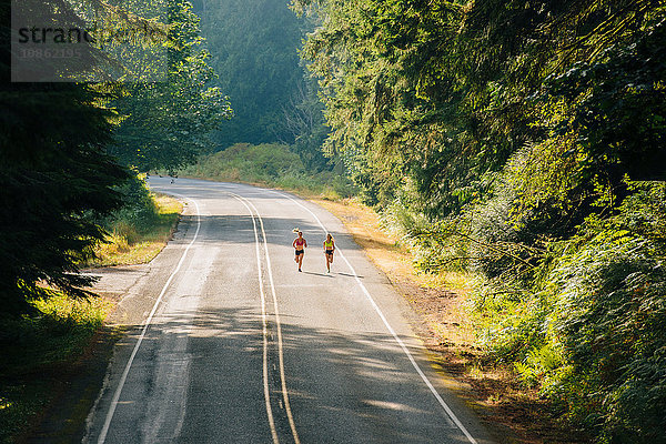 Junge Frau und jugendliches Mädchen rennen entlang einer Landstraße