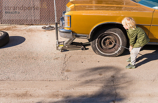 Junge entfernt Radmuttern von einem platten Reifen