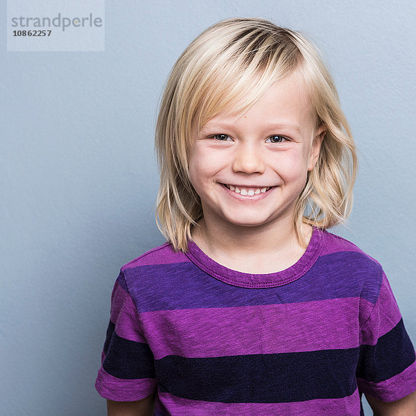 Porträt eines blondhaarigen Jungen  der lächelnd in die Kamera schaut