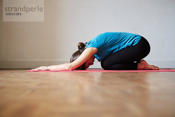 Seitenansicht der nach vorne gebeugten Frau  Hände in Yogastellung auf dem Boden