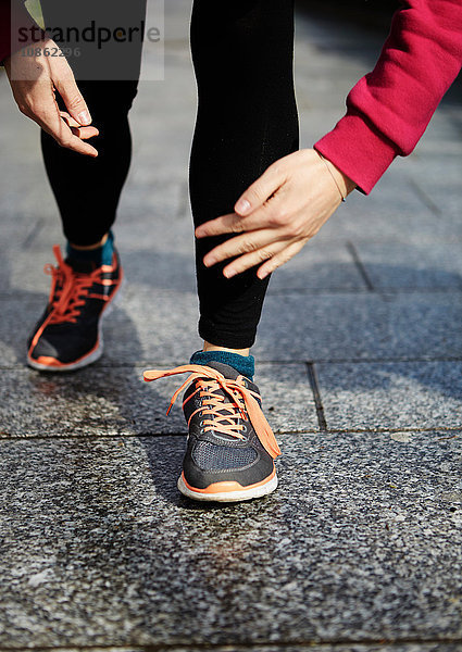 Beine einer Frau mit Laufschuhen auf dem Bürgersteig