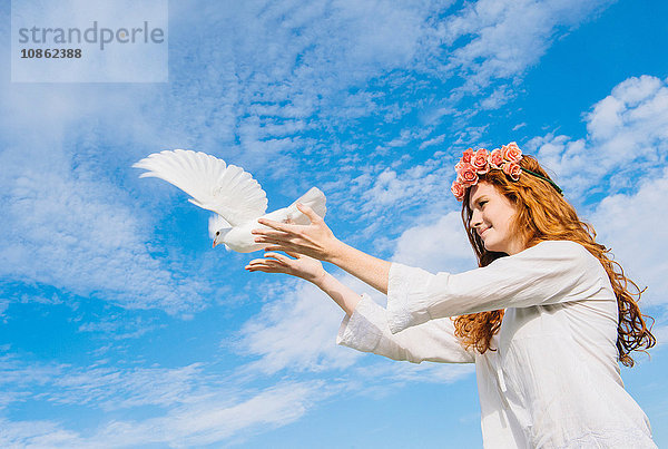 Teenager-Mädchen lässt weiße Taube in den Himmel frei
