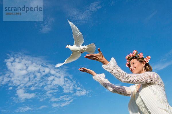 Frau lässt weiße Taube in den Himmel frei