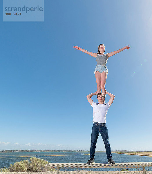 Paar übt Partner-Yoga auf der Strandbank