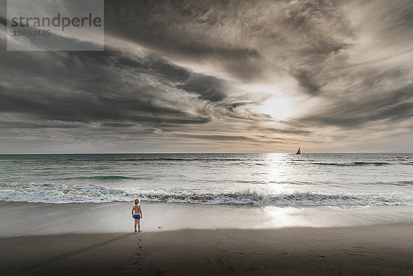 Junge mit Blick auf das Meer und den dramatischen Himmel von Venice Beach  Kalifornien  USA