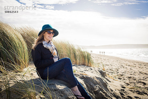 Frau mit Filzhut und Sonnenbrille auf Dünen sitzend  Dillon Beach  Kalifornien  USA