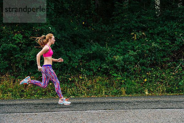 Teenager-Mädchen rennt entlang der Landstraße