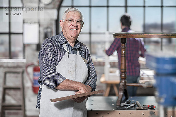 Porträt eines älteren Handwerkers in einer Antiquitäten-Restaurierungswerkstatt