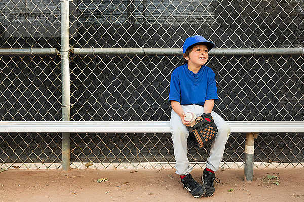 Junge sitzt beim Baseball-Training auf der Bank