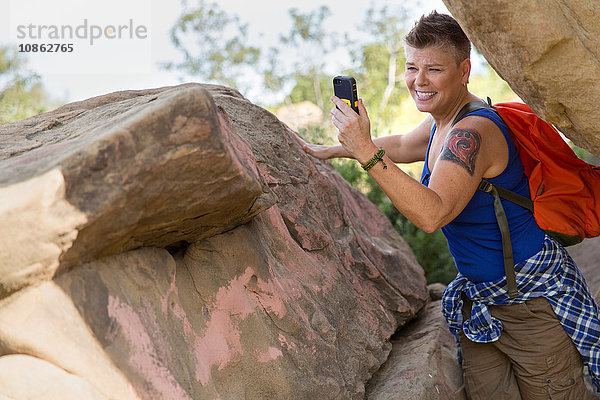 Wanderfrau am Felsen mit Smartphone zum Seflie