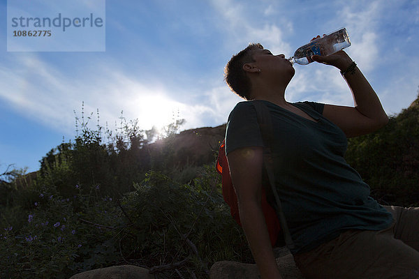 Silhouette einer Frau  die Wasser aus einer Plastikflasche trinkt