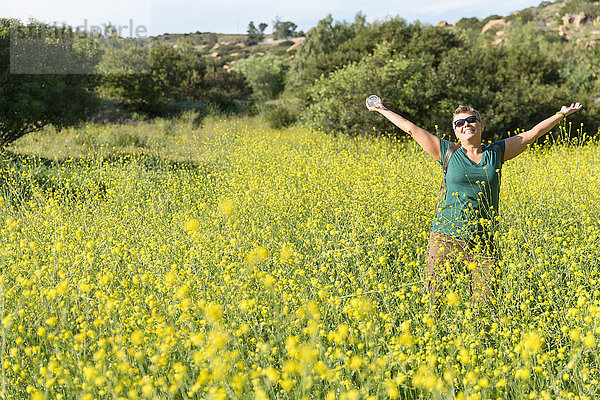 Wanderfrau auf Wildblumenwiese  Arme erhoben