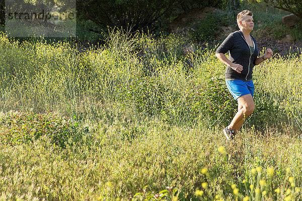 Frau joggt auf Wildblumenwiese