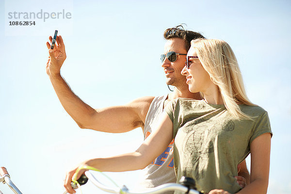 Radfahrendes Paar beim Smartphone-Selfie am Venice Beach  Los Angeles  Kalifornien  USA