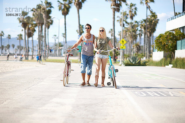 Fahrradfahrerehepaar beim Spaziergang mit dem Fahrrad am Venice Beach  Los Angeles  Kalifornien  USA