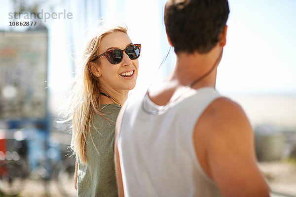 Junge Frau  die sich beim Spaziergang am Venice Beach  Los Angeles  Kalifornien  USA  über die Schulter schaut