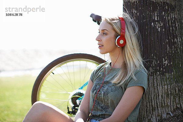 Radfahrerin sitzt am Venice Beach  Los Angeles  Kalifornien  USA  und hört Kopfhörermusik