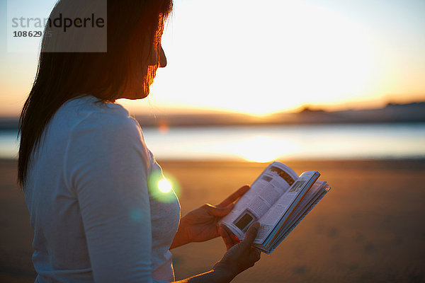 Frau liest Buch am Cannon Beach bei Sonnenuntergang  Kalifornien  USA