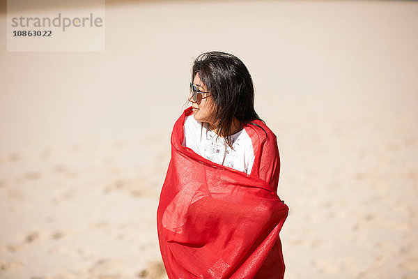 Frau im roten Tuch genießt Strand