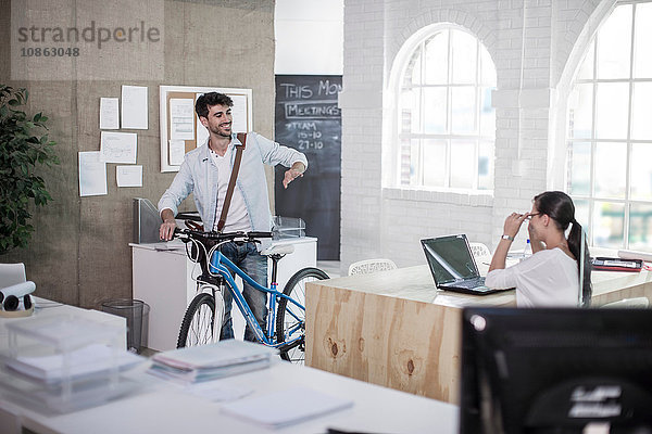 Männlicher Designer verlässt Arbeit mit Fahrrad im Designstudio