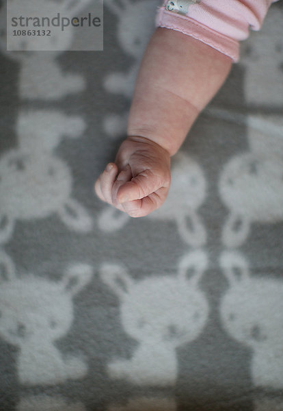 Arm und Hand eines kleinen Mädchens auf einer Decke