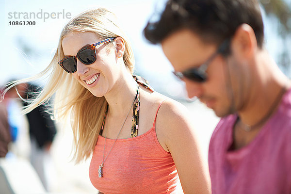 Paar im Freien  Sonnenbrille tragend  lächelnd  Fokus auf junge Frau